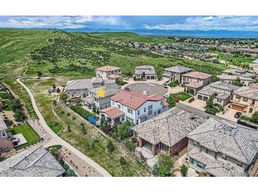 An aerial view showcases a suburban community nestled near rolling hills and mountains on a cloudy day at 9724 Cantabria Pt, Lone Tree, CO 80124