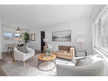 Bright living room featuring a tufted sofa, plush armchairs, and light wood floors at 3137 S Glencoe St, Denver, CO 80222