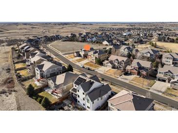 A neighborhood with a green space including two cars parked in front of the house with a mountain view in the background at 15753 E Indian Brook Cir, Parker, CO 80134