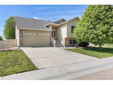 Charming two-story home with a well-manicured lawn and a two car garage on a sunny day at 5210 Roadrunner Ave, Firestone, CO 80504