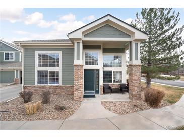 Charming home with green siding, stone accents, and large windows providing ample natural light at 13706 Legend Trail # 104, Broomfield, CO 80023