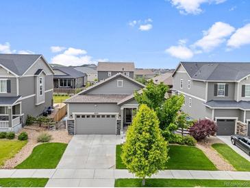 Charming gray home with a well-manicured lawn and lovely landscaping creating wonderful curb appeal at 18036 E 99Th Ave, Commerce City, CO 80022