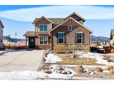 Charming two-story home with stone accents and a well-maintained front yard on a sunny day at 9335 Dunraven Loop, Arvada, CO 80007