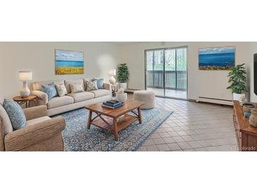 Bright living room with a plush sofa, blue accent rug, and sliding glass doors to a balcony at 6960 E Girard Ave # 105, Denver, CO 80224