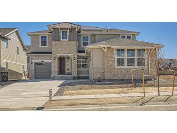 Charming two-story home featuring a stone and siding facade with an attached garage and a well-manicured lawn at 635 Twilight St, Erie, CO 80516