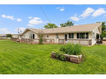 Expansive backyard featuring a well-maintained lawn and a wooden deck along the back of the house at 20995 County Road 28, Hudson, CO 80642