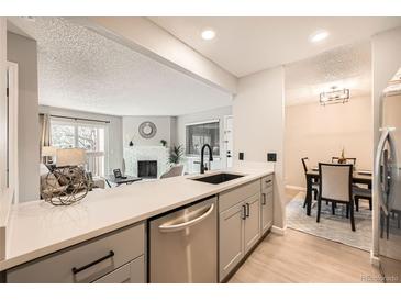 Open-concept kitchen with stainless steel appliances and views into the living room and dining area at 14602 E 2Nd Ave # 200C, Aurora, CO 80011