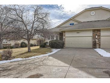 Tan two-story home with attached garage and landscaping at 10054 W Vassar Pl, Lakewood, CO 80227