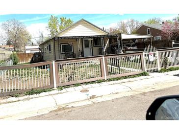 Charming single-Gathering home featuring a covered porch and a classic picket fence, with a carport on the right side at 4411 W Center Ave, Denver, CO 80219