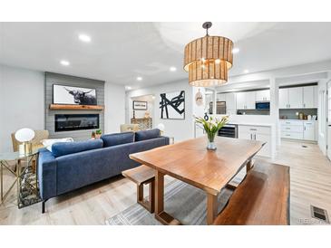 Bright living room with modern fireplace, light wood floors, and dining table at 3067 Robin Way, Denver, CO 80222