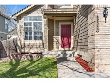 Inviting front entrance with a red door, set amidst a well-maintained lawn and tidy landscaping at 12535 Forest View St, Broomfield, CO 80020