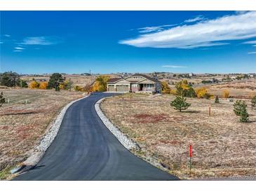 Inviting ranch-style home featuring a long, private driveway and mature trees under a beautiful blue sky at 2601 Loyd Cir, Parker, CO 80138