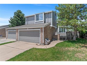 Charming two-story home with a well-manicured lawn, gray siding, brick accents, and an attached two-car garage at 3871 E Euclid Ave, Centennial, CO 80121