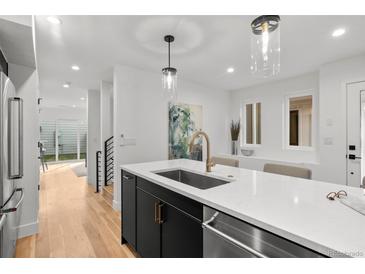 Beautiful kitchen features sleek black cabinetry, stainless steel appliances, quartz countertops, and modern pendant lighting at 2451 Lawrence St # 2, Denver, CO 80205