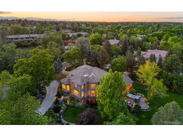 Stunning home featuring a lush landscaped yard, driveway, and outdoor spa at 7050 S Polo Ridge Dr, Littleton, CO 80128