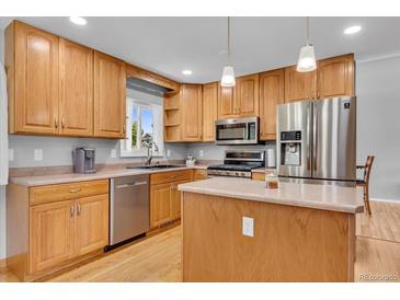 Bright kitchen features stainless steel appliances, light wood cabinets, and a functional center island at 16941 E Eastman Pl, Aurora, CO 80013