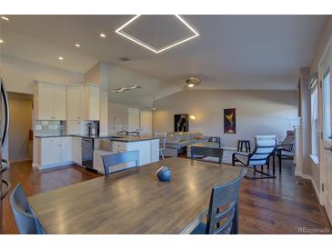 Open-concept living space featuring a modern kitchen, dining area, and comfortable seating with lots of natural light and wood floors at 19563 E Ithaca Pl, Aurora, CO 80013