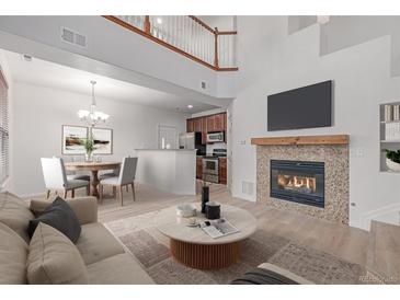 Bright living room with a cozy fireplace, TV and dining area with modern chandelier at 7777 E 23Rd Ave # 1406, Denver, CO 80238