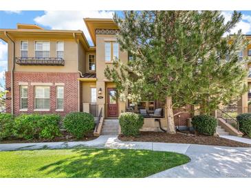 Inviting townhome featuring a well-manicured lawn, brick accents, and a charming front porch area for relaxing at 7812 Inverness Blvd, Englewood, CO 80112