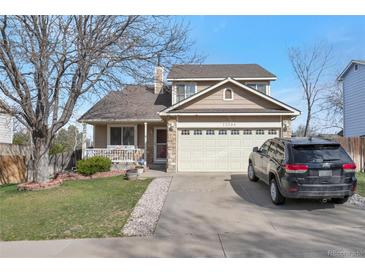 Charming two-story home with a manicured lawn, covered porch, and a two-car garage at 12134 Glencoe St, Thornton, CO 80241