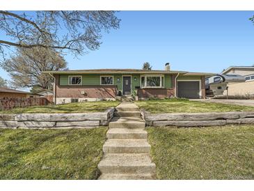 Charming single-story home with a well-manicured lawn and inviting front entrance with beautiful steps at 1465 S Urban Way, Lakewood, CO 80228