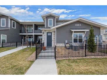 Charming townhouse with gray siding, stone accents, a black fence, and well-maintained landscaping at 350 High Point Dr # C201, Longmont, CO 80504