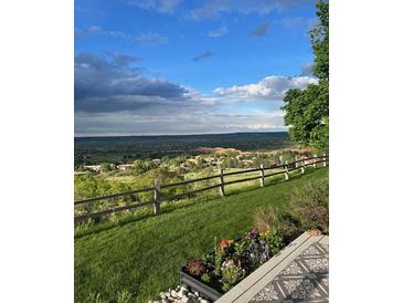 Expansive scenic view from the property overlooking lush greenery, a wooden fence, and a beautiful sky above at 6980 Fargo Trl, Littleton, CO 80125