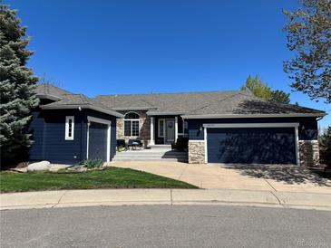 Charming home featuring a 3-car garage, stone accents, blue exterior paint, manicured lawn, and inviting curb appeal at 10233 Greatwood Ct, Highlands Ranch, CO 80126