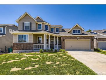 Charming two-story home with a welcoming porch and a well-maintained lawn on a sunny day at 16534 E Fire Fly Ave, Parker, CO 80134