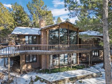 Beautiful mountain home with a wooden deck and large windows showcasing the scenic views at 9142 Warriors Mark Dr, Franktown, CO 80116