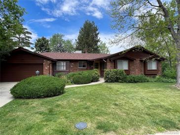 Charming single-story home with brick and wood exterior, lush green lawn, and mature trees at 12075 W 18Th Dr, Lakewood, CO 80215