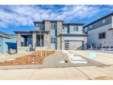 New construction home featuring stone accents, a modern garage door and professional landscaping at 8596 Hotchkiss St, Littleton, CO 80125