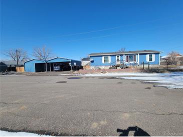 Charming home featuring a spacious carport, painted in a coordinated blue tone at 313 W 3Rd Ave, Byers, CO 80103