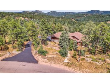 Rustic-style home nestled in a lush forest setting with a winding driveway and mountain views at 7790 S Homesteader Dr, Morrison, CO 80465