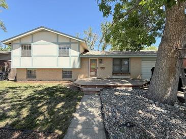 Charming home featuring a brick facade, a wooden porch, mature trees, and easy access via the concrete walkway at 7195 E Louisiana Ave, Denver, CO 80224