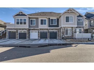 Modern townhome exterior with gray siding, stone accents, and individual garages, showcasing contemporary design at 23688 E Ida Dr # E, Aurora, CO 80016