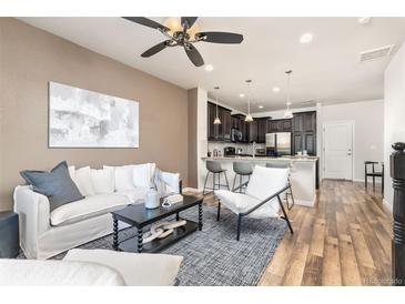 Bright open-concept living room features a ceiling fan and modern kitchen with breakfast bar at 8183 S Yosemite Ct, Centennial, CO 80112