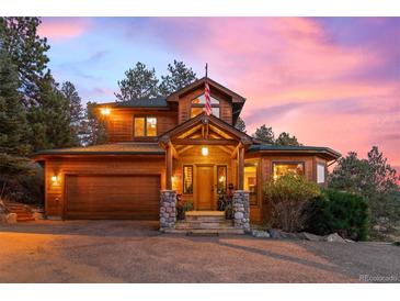 Stunning craftsman home with an attached garage, stone accents, a charming front porch and beautiful outdoor lighting at 394 S Ponderosa Way, Evergreen, CO 80439