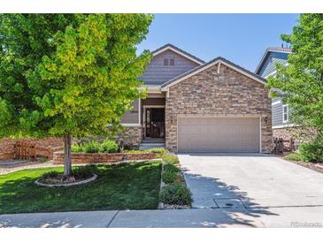 Charming home featuring stone accents, a well-manicured lawn, and a spacious two-car garage at 13986 Lexington Dr, Parker, CO 80134