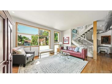 Bright living room with large windows, hardwood floors, and an open staircase at 396 E Warren Ave, Denver, CO 80210