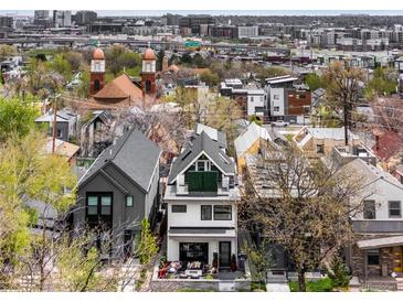 An aerial view of a modern home with a rooftop deck and a city skyline backdrop at 3540 Pecos St, Denver, CO 80211