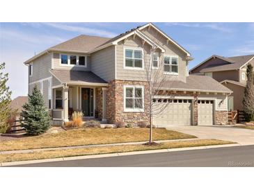 Inviting two-story home boasts a neutral exterior with a manicured front lawn and attached garage at 13507 W 87Th Ter, Arvada, CO 80005