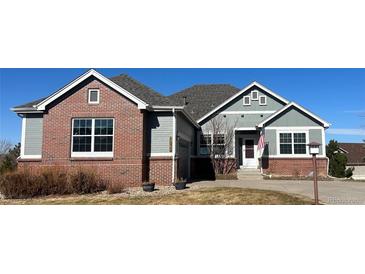 Charming home with a brick and gray facade, complemented by a well-maintained yard and an American flag at 22725 E Long Dr, Aurora, CO 80016