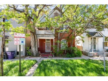 Charming two-story brick home with a cozy front porch and lush green lawn, shaded by mature trees at 2410 W 36Th Ave, Denver, CO 80211