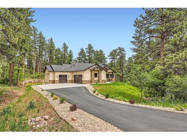 Sprawling ranch-style home with a three-car garage, stone accents, and private drive surrounded by lush trees at 8280 Bannock Dr, Larkspur, CO 80118