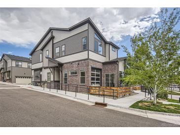 Beautiful modern home featuring mixed siding, brick accents, a unique garage door window, and a welcoming outdoor patio at 10117 Morrison Rd, Lakewood, CO 80227