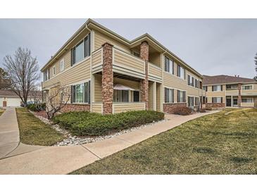 Two-story exterior elevation with light yellow siding, stone accents, and a well-maintained landscape at 16828 E Gunnison Dr # 7H, Aurora, CO 80017