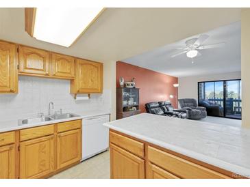 Bright kitchen featuring wood cabinets, white countertops, and appliances open to the living room at 14001 E Marina Dr # 607, Aurora, CO 80014