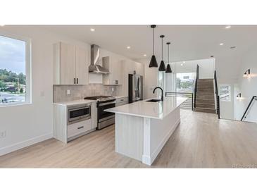 Bright modern kitchen boasts stainless steel appliances, an island, and sleek minimalist finishes at 10157 W 38Th Ave, Wheat Ridge, CO 80033