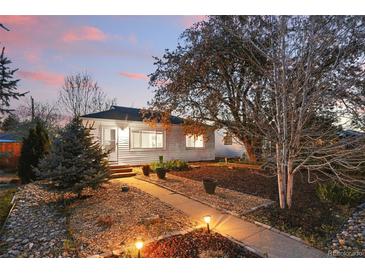 Charming home with a beautifully landscaped front yard, stone pathway, and flowering trees at dusk at 1711 Spruce St, Denver, CO 80220